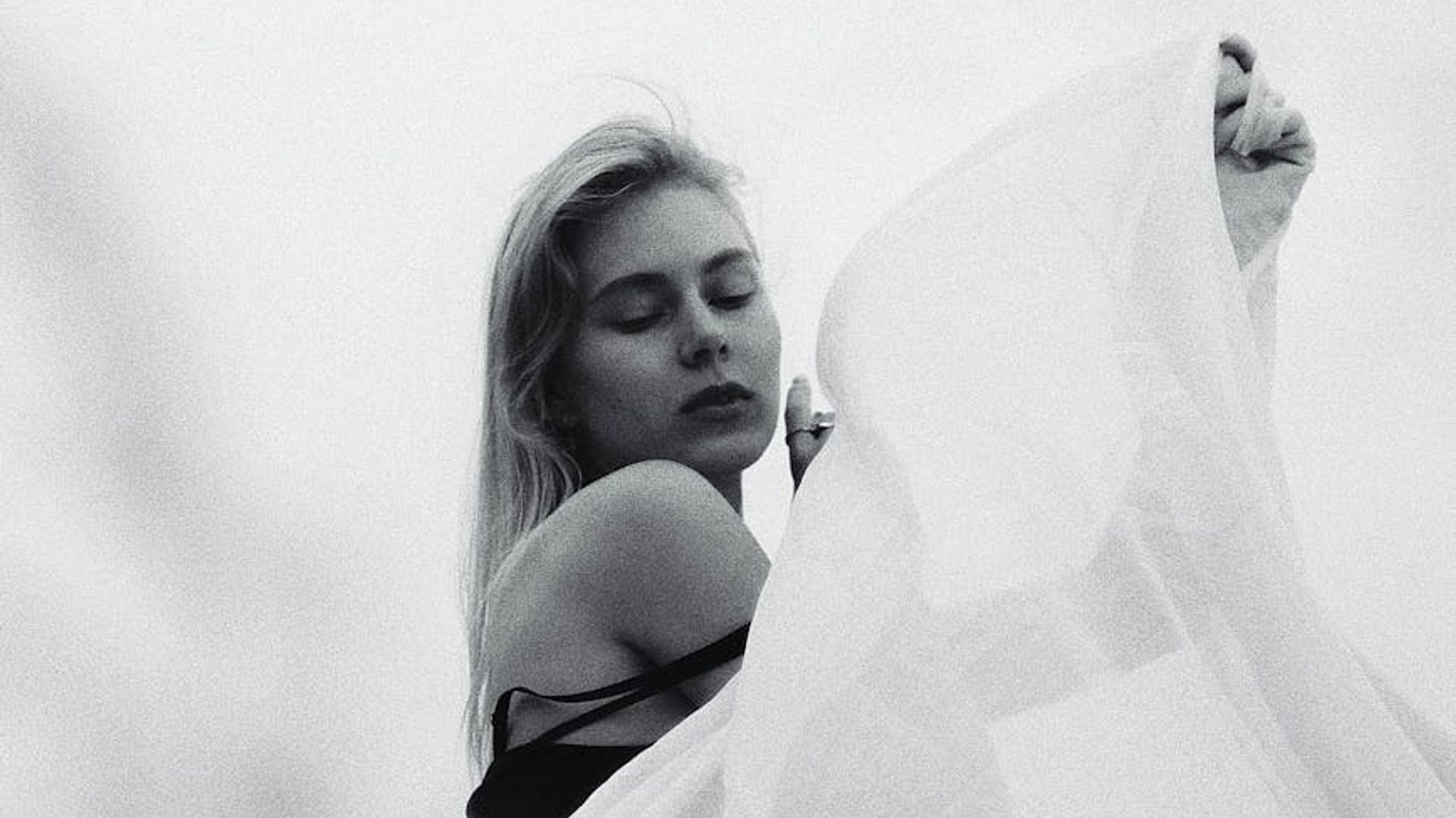 A person in a calm, flowing movement pose in a minimalist space.